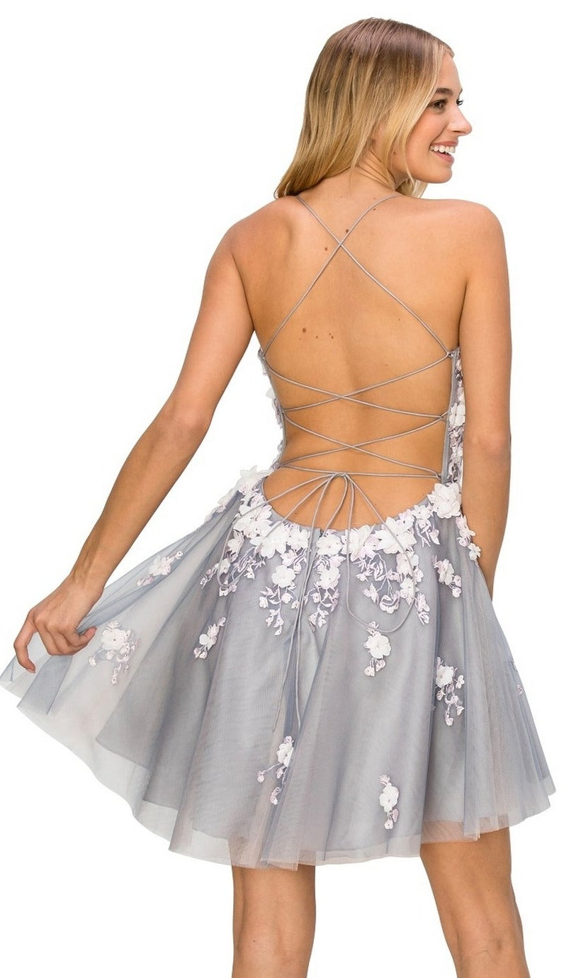 Smiling woman faces away in the Backless Sheer-Waist Floral Homecoming Dress 8053J—a light blue short dress with crisscross lace-up straps and delicate 3-D flowers.